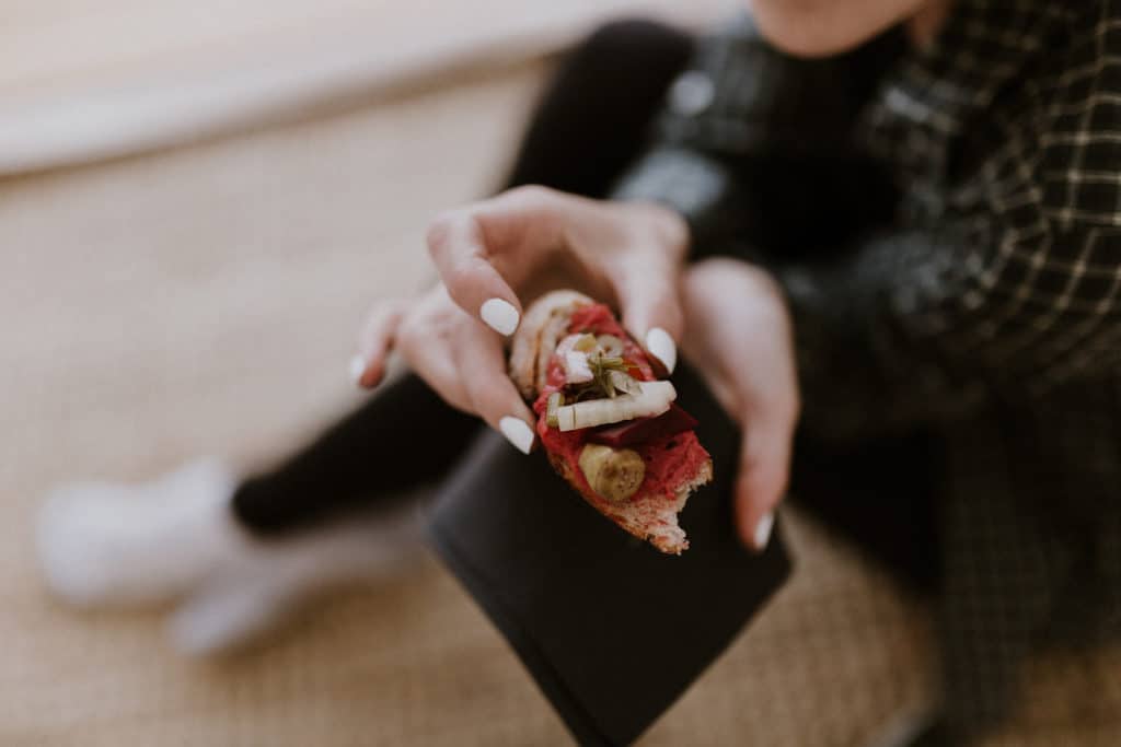 Girl with White Nail Polish Holding Bread with Red Beet Hummus Pickled Onions